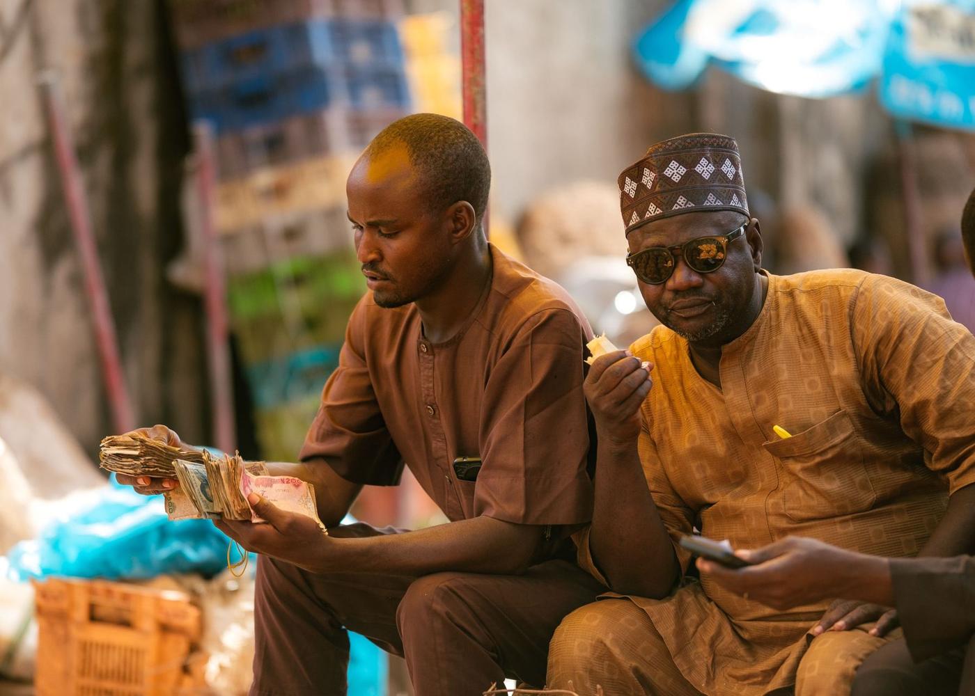 Two traders in a market counting naira notes together